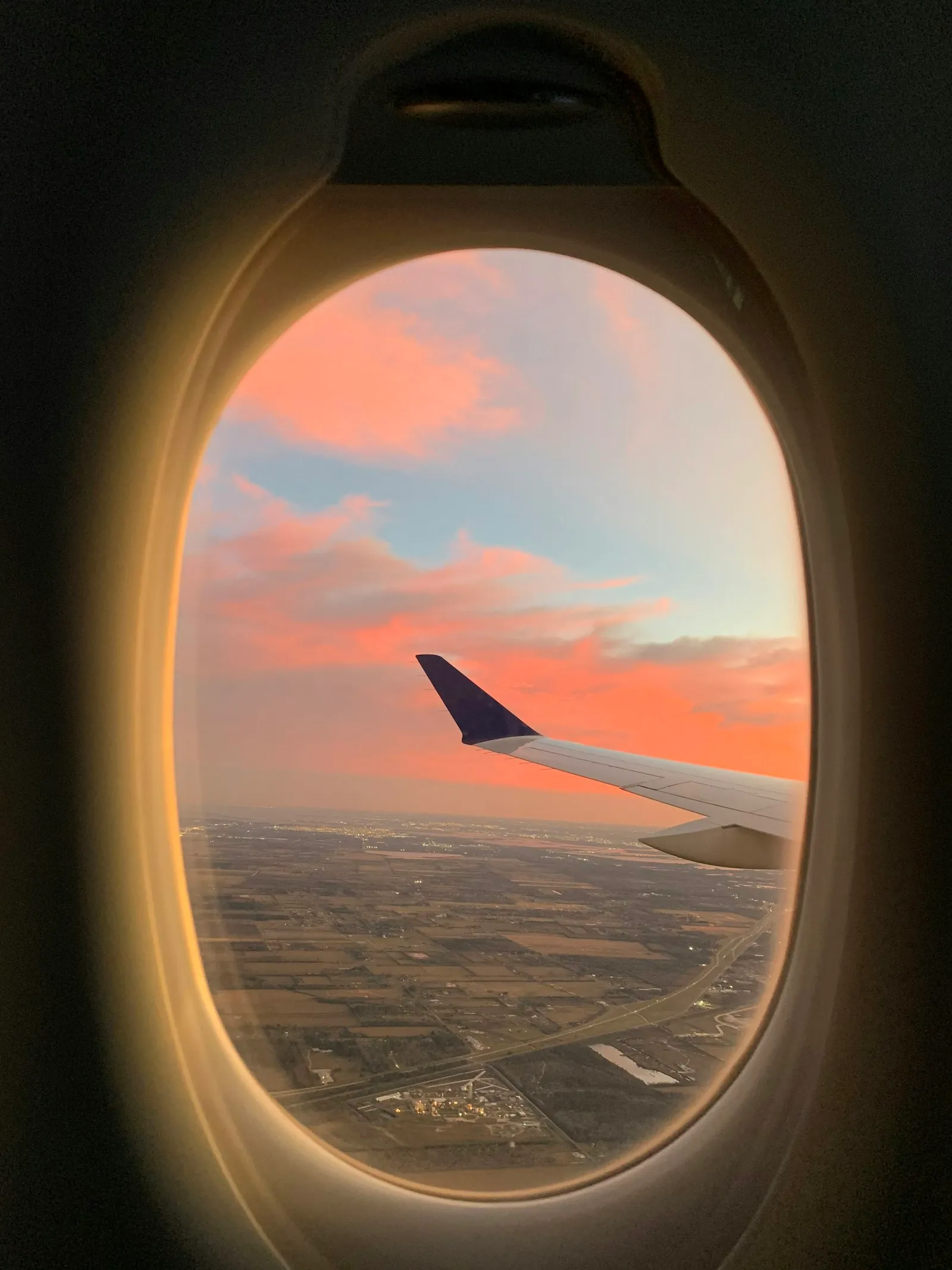 A pink evening sky seen through an airplane window