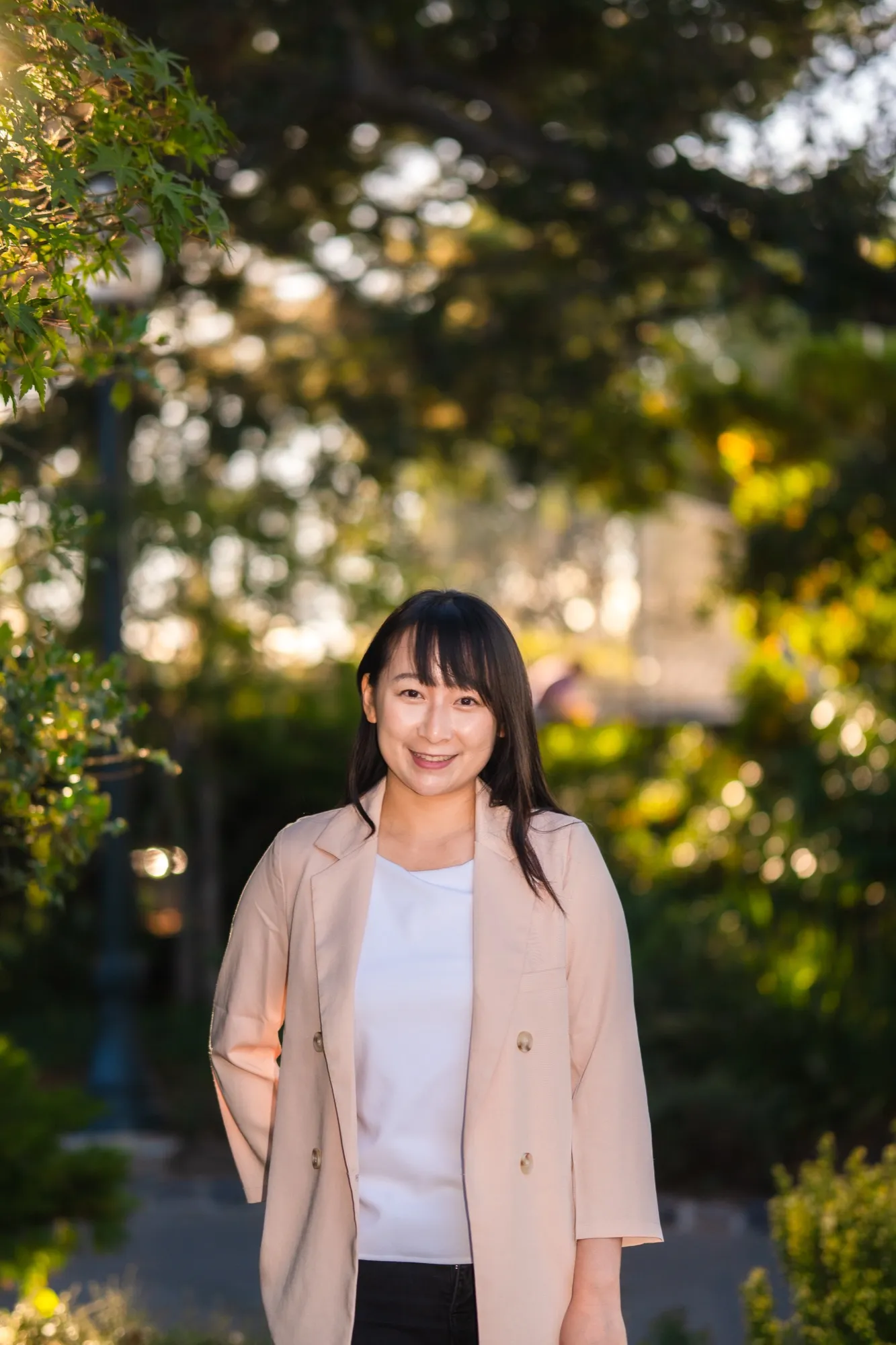 Asian American therapist Zi Zheng standing under a tree in warm backlight, SF Bay Area