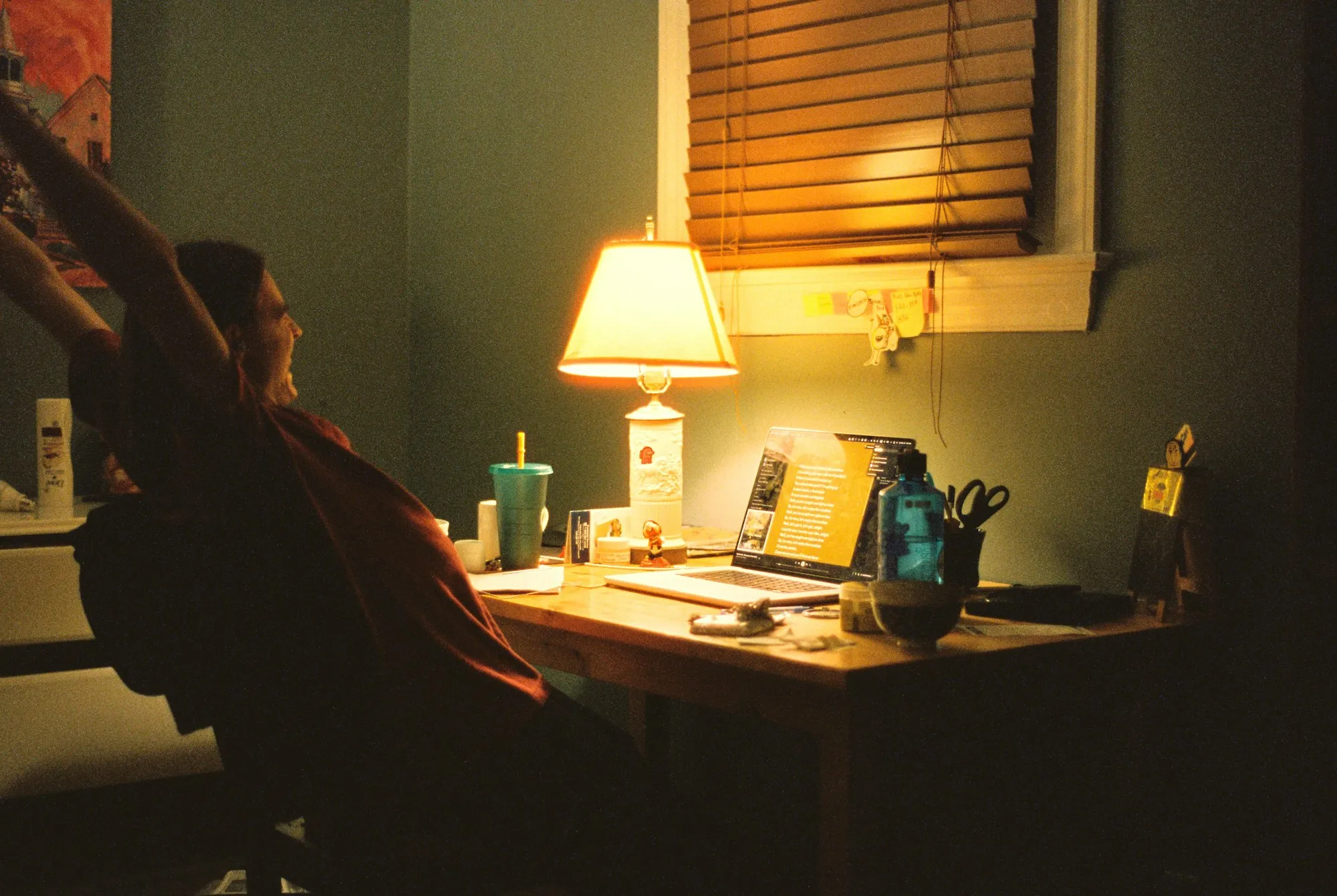 A weary stretch under a lone desk lamp, late at night