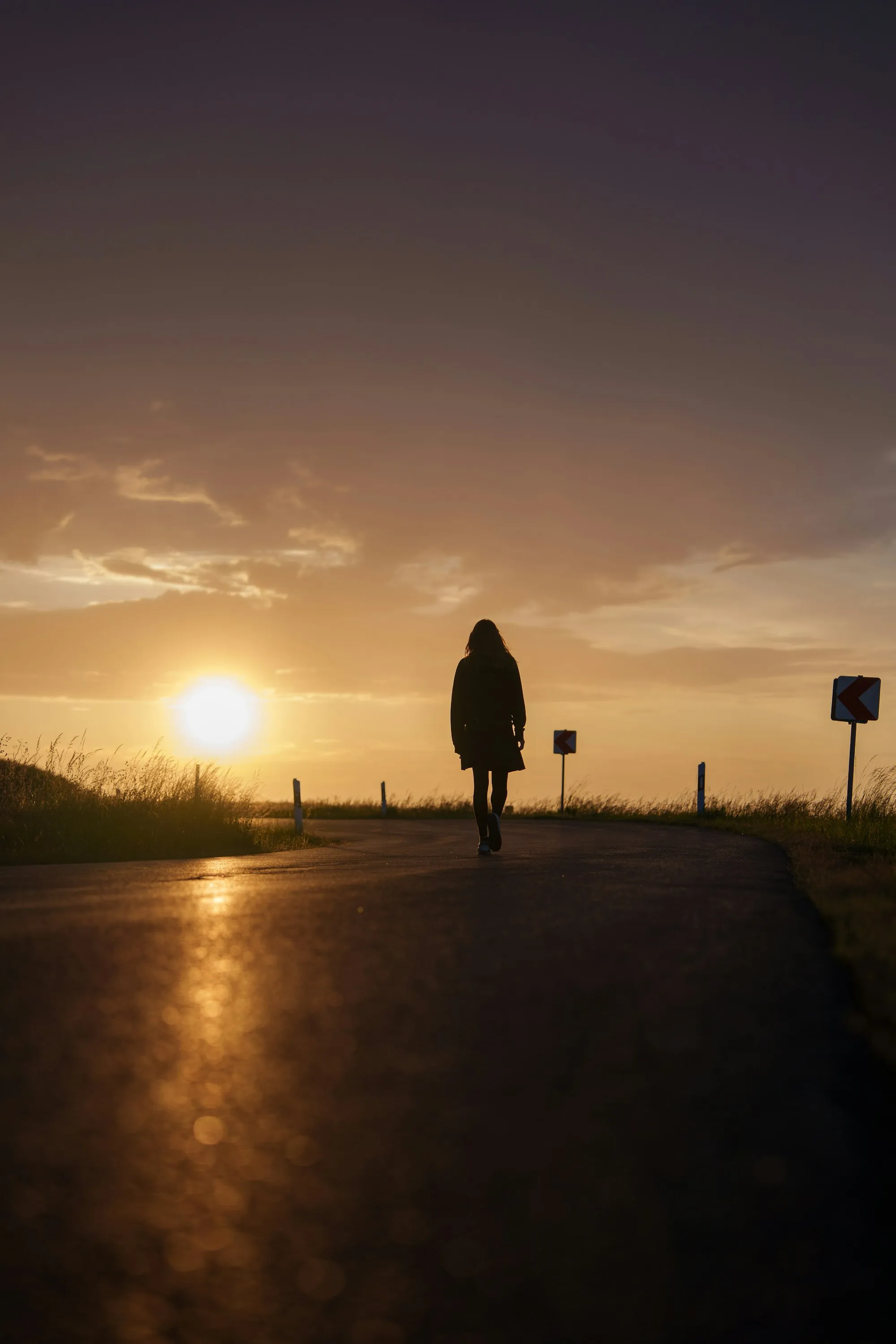A lone figure walking toward a dramatic sky