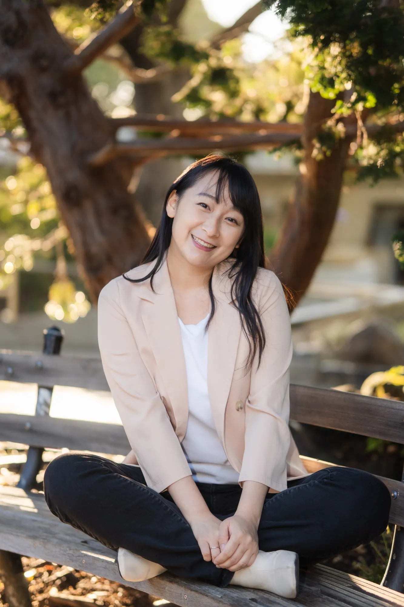 Zi Zheng, Mandarin speaking therapist in the Bay Area, smiling on a park bench under a tree