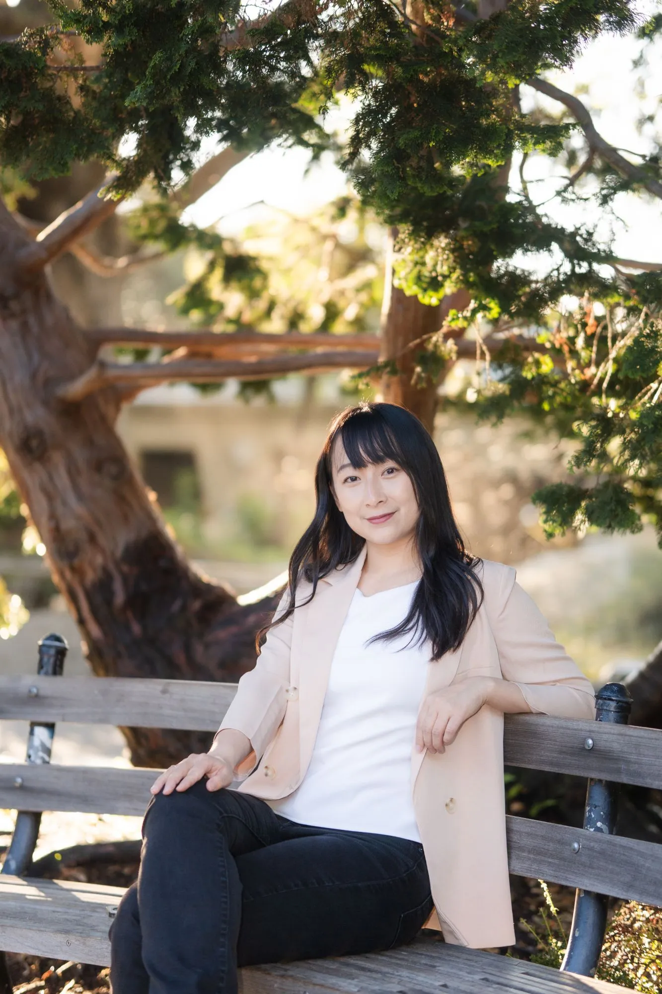 Therapist Zi Zheng, seated on a bench under a tree